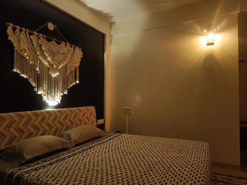 sypialnia z łóżkiem i żyrandolem na ścianie w obiekcie Nagarik Commune, Baner - Pune w mieście Pune