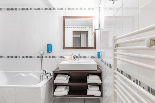 a white bathroom with a sink and a tub at Appart'City Classic Nantes - Carquefou in Carquefou