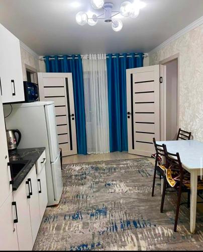 eine Küche mit einem Tisch und eine Küche mit blauen Vorhängen in der Unterkunft Tumar Guest House in Naryn