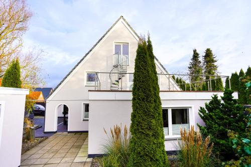 a white house with trees in front of it at Ferienhaus Auszeit - Wohnung "Strandmuschel" in Grömitz