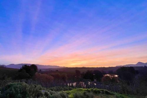 a sunset over a field with mountains in the background at Elgin Views Annex in Ouda Brug