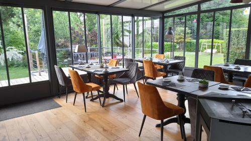 a restaurant with tables and chairs and large windows at Hôtel Quai des Pontis in Cognac