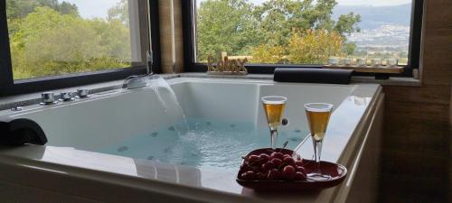 uma banheira com 2 taças de champanhe e uma taça de fruta em Villa Regadio na Covilhã