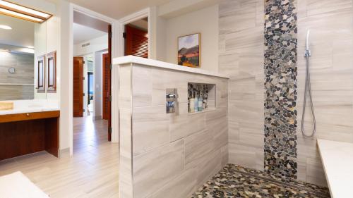 La salle de bains est pourvue d'une douche et d'un lavabo. dans l'établissement THE POINT Contemporary 2BR Mauna Lani Point Home with Ocean View, à Waikoloa