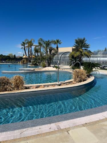 une piscine avec des palmiers dans un complexe hôtelier dans l'établissement Camping les dunes 5 étoiles mobil home 6 personnes A14, à Torreilles