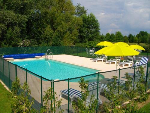 uma piscina com dois guarda-sóis e cadeiras e uma piscina em Golf Hotel Colvert - Room Service Disponible em Levernois