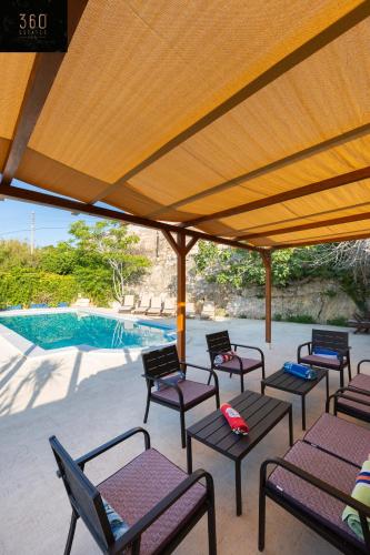 a group of chairs under a pavilion next to a pool at Spacious Villa with Private Pool & BBQ in St'Pauls by 360 Estates in St. Paul's Bay