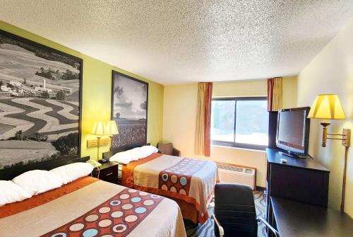 a hotel room with two beds and a flat screen tv at Super 8 by Wyndham Newton in Newton