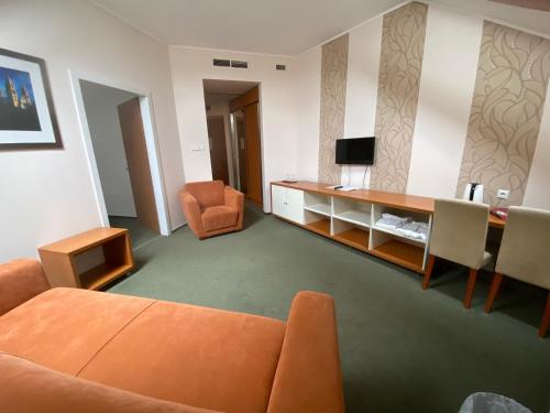 a living room with an orange couch and a desk at Boutique Hotel Sopianae in Pécs