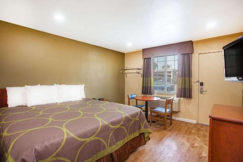 Super 8 by Wyndham Redlands/San Bernardino في ريدلاندز: غرفه فندقيه بسرير وطاولة وتلفزيون