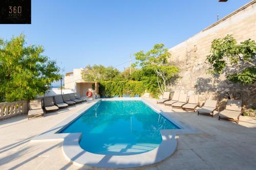 a swimming pool with chaise lounge chairs next to a building at Spacious Villa with Private Pool & BBQ in St'Pauls by 360 Estates in St. Paul's Bay