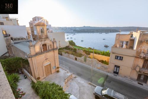 a building with a clock tower next to the water at Spacious Villa with Private Pool & BBQ in St'Pauls by 360 Estates in St. Paul's Bay