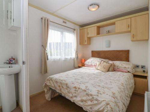 プスヘリにあるTir Glyn Caravanのベッドルーム1室(ベッド1台、シンク、窓付)