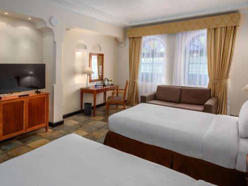 a hotel room with two beds and a flat screen tv at Novotel Bahrain Al Dana Resort in Manama