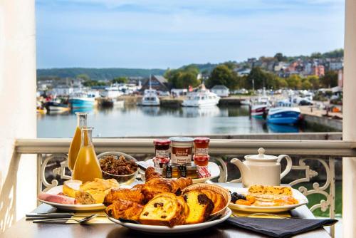 Una mesa de desayuno con pan y pasteles y una vista de un puerto en Best Western Le Cheval Blanc -Vue sur le port-plein centre ville, en Honfleur