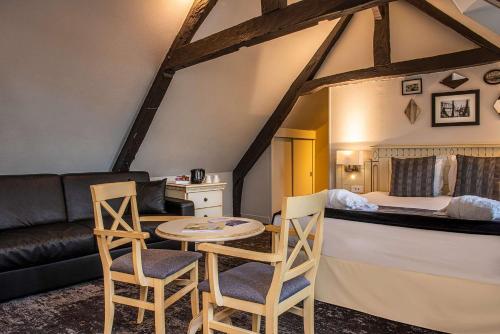 uma sala de estar com um sofá, uma mesa e cadeiras em Best Western Le Cheval Blanc -Vue sur le port-plein centre ville em Honfleur