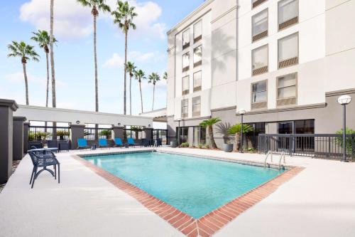 a swimming pool in front of a building with palm trees at Hampton Inn Laredo in Laredo