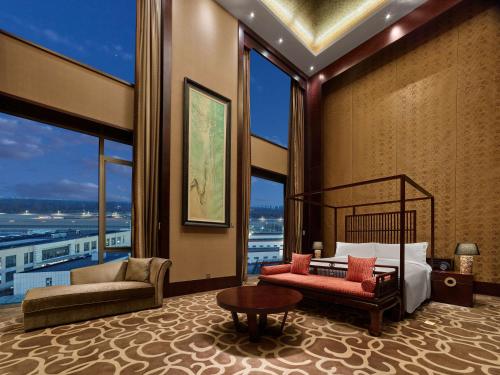 a bedroom with a bed and a couch and windows at Hilton Beijing Capital Airport in Shunyi