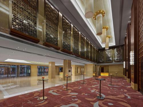 a lobby with tables in the middle of a building at Hilton Beijing Capital Airport in Shunyi