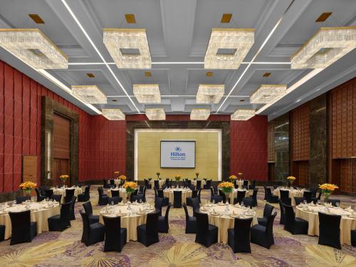 a banquet hall with tables and chairs and a screen at Hilton Beijing Capital Airport in Shunyi