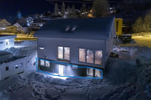 uma casa com luzes acesas na neve à noite em Apartment in Lillestrøm with free parking and great view em Lillestrøm