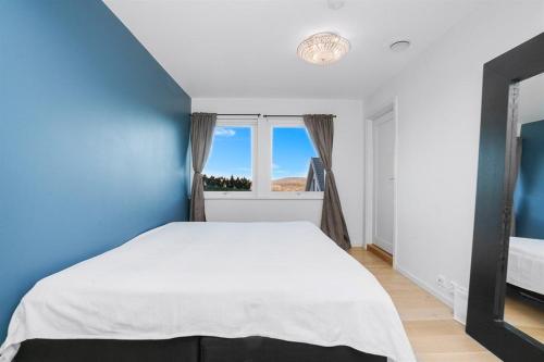 um quarto com uma cama branca e uma parede azul em Apartment in Lillestrøm with free parking and great view em Lillestrøm