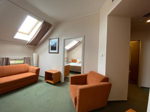 een woonkamer met oranje meubels en een slaapkamer bij Boutique Hotel Sopianae in Pécs