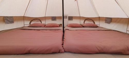 - 2 lits dans une tente avec des draps et des oreillers roses dans l'établissement Sky Camping, à Củ Chi