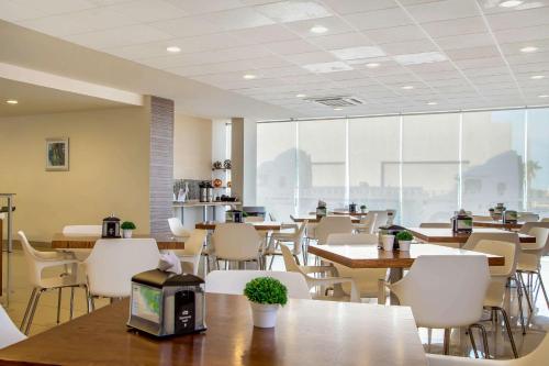 an empty restaurant with tables and chairs and windows at Sleep Inn Hermosillo in Hermosillo