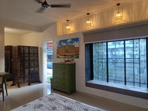 a bedroom with a large window and a green dresser at Nagarik Commune, Baner - Pune in Pune