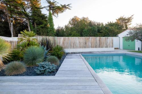 un jardin avec une piscine et une clôture en bois dans l'établissement Maison pour 10 personnes au centre de la Flotte, à La Flotte