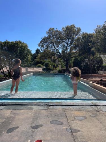 Dos chicas están de pie en una piscina en VILLA VUE MER AVEC PISCINE PRIVÉE pour 4 à 6 Personnes WIFI, en Saint-Aygulf