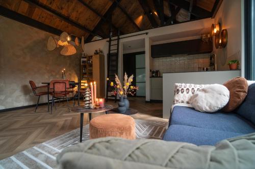 a living room with a blue couch and a table at Fantastisch luxe boshuis I Onthaasten in de natuur in Emst