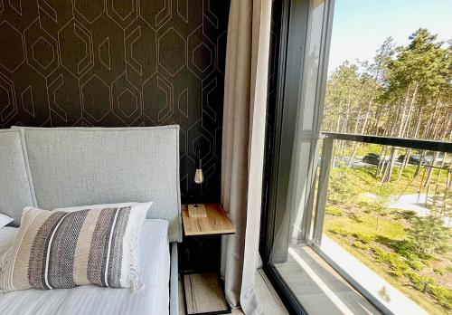 a bedroom with a bed next to a window at Shellter Prestige Przy Wydmie in Rogowo