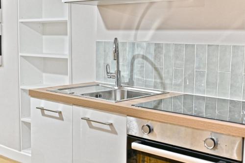 une cuisine avec un évier en acier inoxydable et des armoires blanches dans l'établissement Appartement 3 chambres proche Châtelet-Les Halles, à Paris