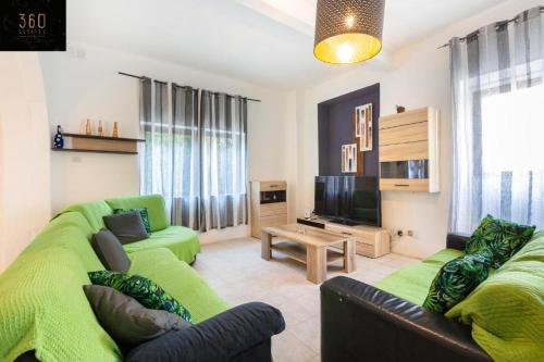 un soggiorno con un divano verde e una televisione di Spacious Villa with Private Pool & BBQ in St'Pauls by 360 Estates a San Pawl il-Baħar
