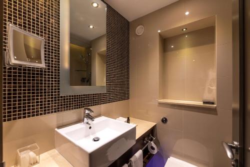 a bathroom with a sink and a mirror at 100 Queen's Gate Hotel London Kensington, Curio Collection by Hilton in London