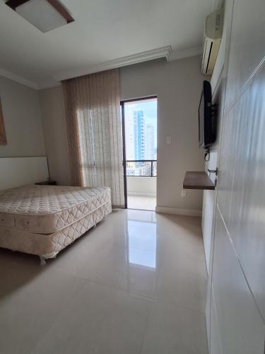 a bedroom with a bed and a large window at Apto com sacada in Balneário Camboriú