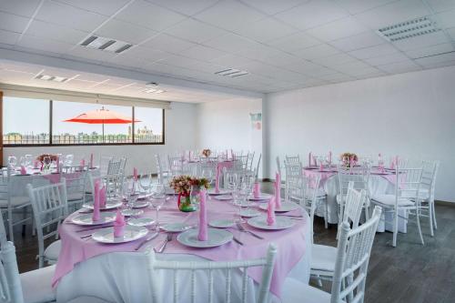 a room with tables and white chairs and pink tables and chairsktop at Sleep Inn Puebla Centro Hist rico in Puebla