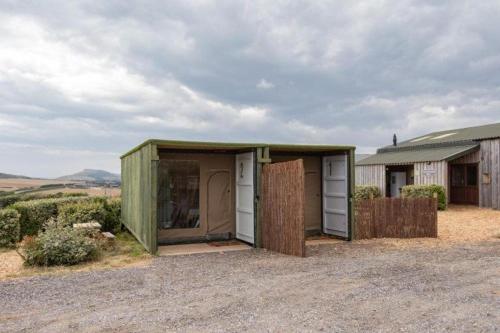 a green shed with two doors in a field at Container 5, Camp Tapnell in Yarmouth