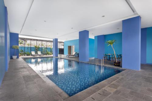 a swimming pool in a building with blue walls at Arte Hotel Bandar Lampung in Bandar Lampung