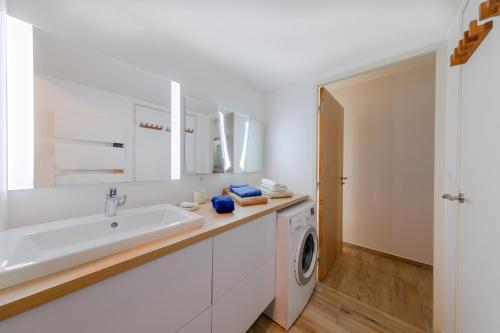 Un baño blanco con lavabo y lavadora. en Résidence Le Rêve Apt 209, en La Tranche-sur-Mer