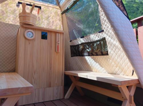 a sauna with a bench and a clock in a tent at SMART VILLA Hakone Sukumogawa Riverside in Hakone
