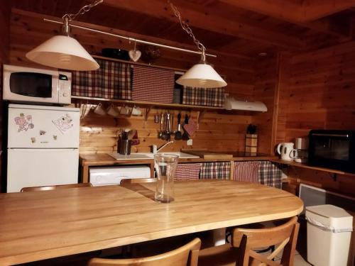 une cuisine avec une table en bois, des chaises et des appareils électroménagers dans l'établissement Chalet bois 45M2, à Bolquère-Pyrénées 2000