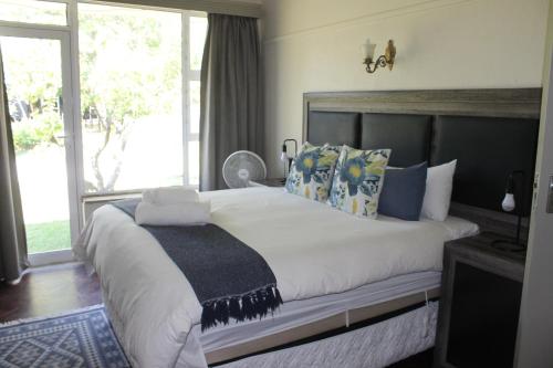 a bedroom with a large bed with a large window at Berry Lane Guesthouse in Kroonstad