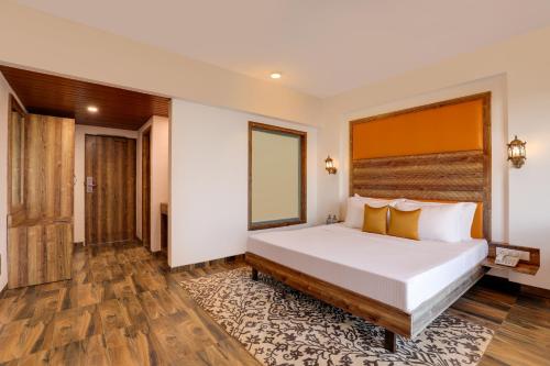 a bedroom with a large bed and wooden floors at Lemon Tree Hotel, Dapoli in Dapoli