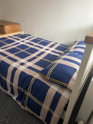 a blue and white comforter on a bed at Self contained room, en-suite with separate lockable front door, located in an exclusive area in Wednesbury