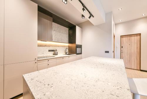 a kitchen with white cabinets and a marble counter top at Apartments near Ozas in Vilnius