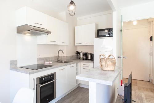 une cuisine avec des armoires blanches et un comptoir dans l'établissement Studio Antibes 5min Train Station & Sea - AC & Balcony, à Antibes