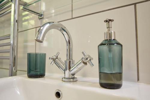 a sink with a glass bottle next to a faucet at Premium Central Stroud Apartment with Parking x2 in Stroud